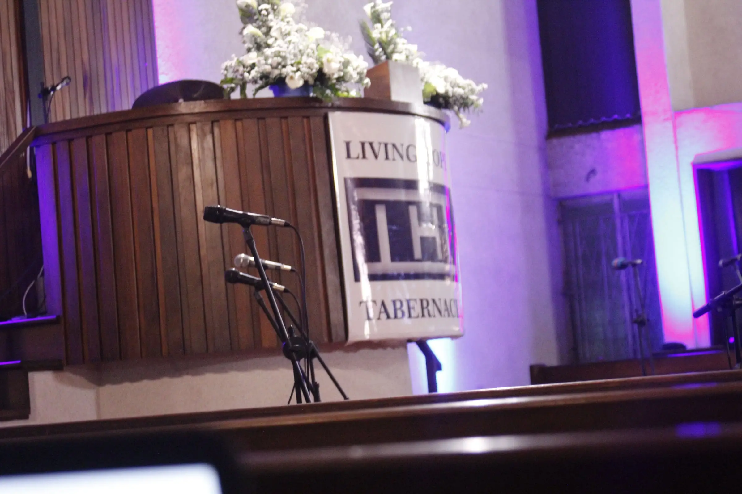 The pulpit of Living Hope Tabernacle with the church banner, lit in blue and violet